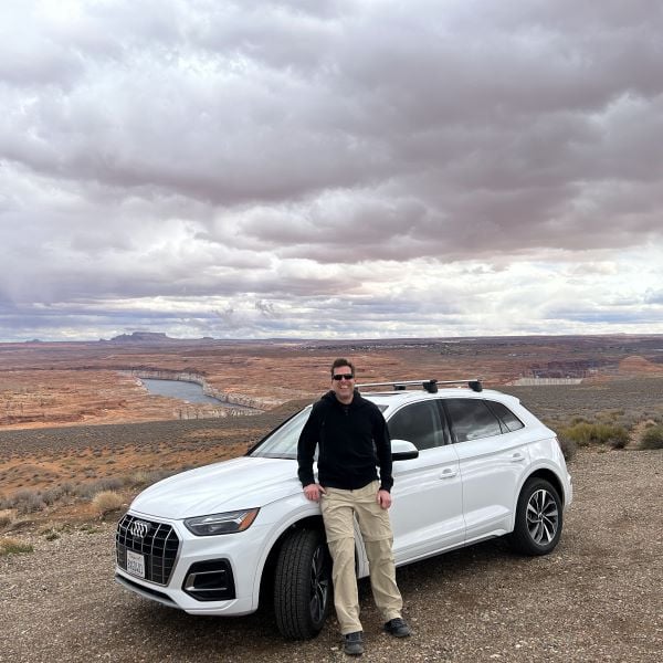 A man standing in front of a white Audi SUV near Glen Canyon Dam in Arizona.